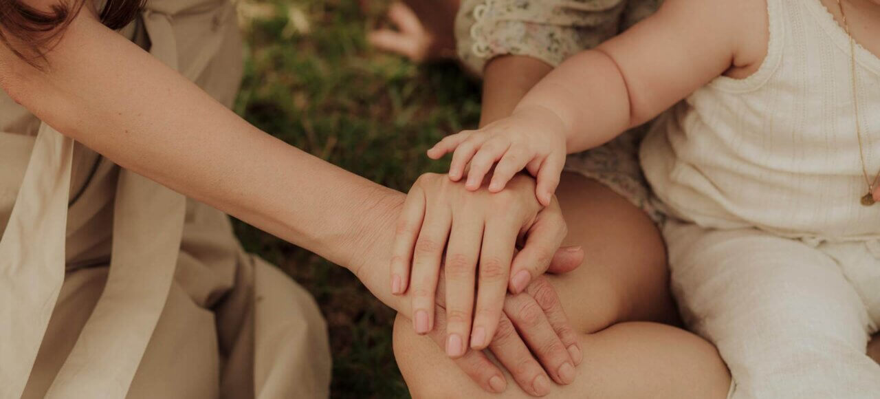 Child’s hand resting on parent’s hands, symbolizing family unity and emotional support in child support cases