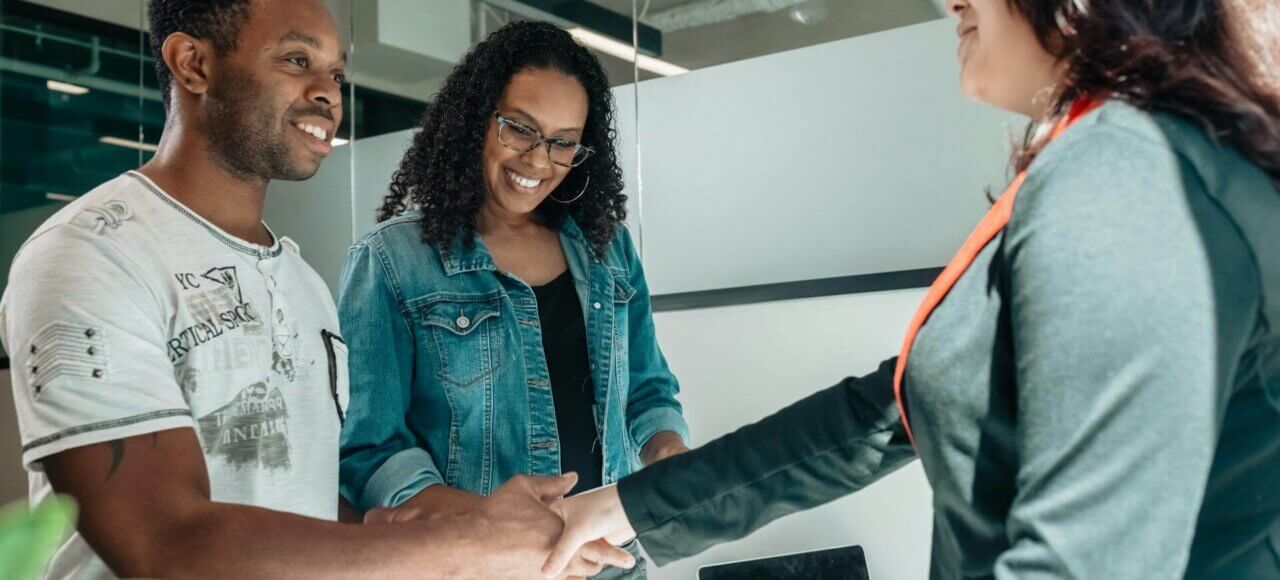 Smiling couple shaking hands with attorney, discussing prenuptial or postnuptial agreements