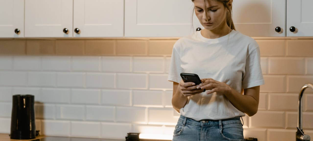 Woman standing alone looking at phone, representing domestic violence or restraining order situations