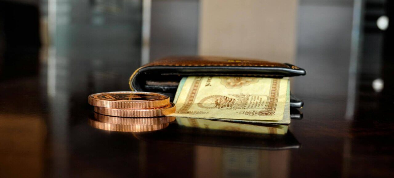 Wallet with cash and coins on table, symbolizing division of assets and debts in divorce